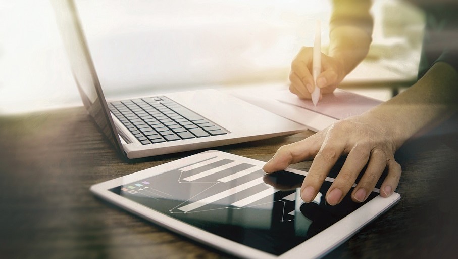Mann arbeitet an Laptop und Tablet